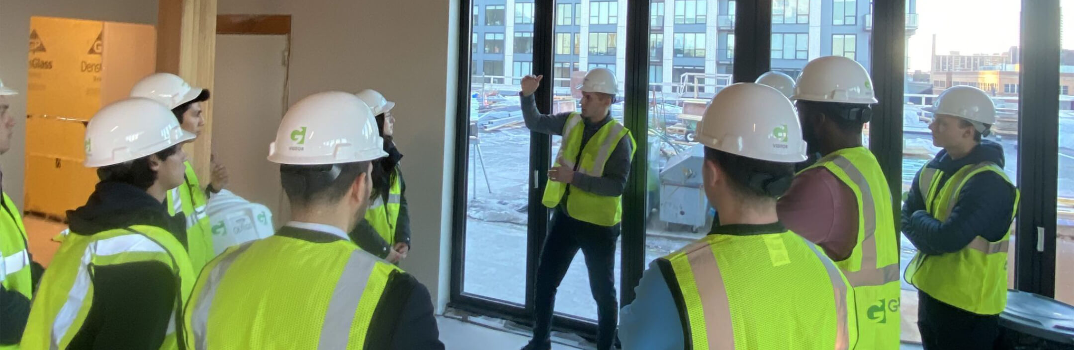 Group of people in hard hats and vests discussing construction of a building