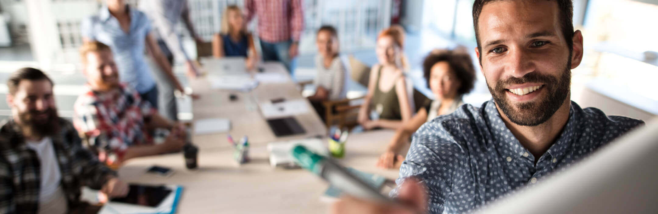 Group of people in a meeting and someone writing on a whiteboard