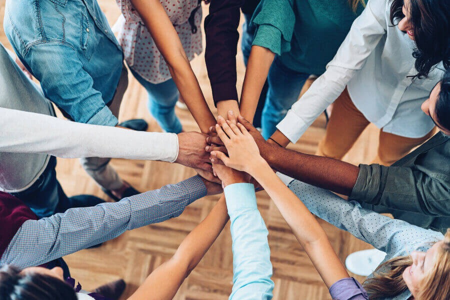 Group of people putting their hands together in the middle of a circle